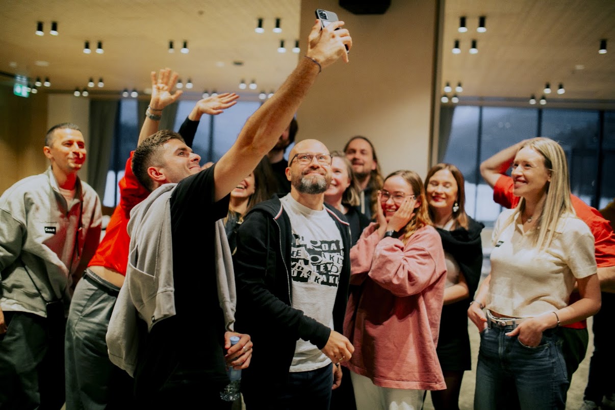 Nasmejana ekipa med skupinskim selfijem
